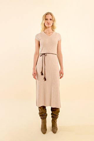 A person faces forward in the Molly Bracken Ribbed Knitted Midi Dress—a light beige, short-sleeved, midi-length style with a woven self-tie belt—paired with slouchy taupe boots against a plain beige background.