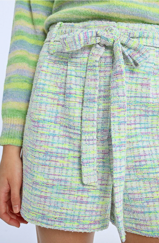 A person is wearing Molly Bracken Knit Self-Tie Belt Shorts and a knit sweater with green, yellow, and lavender stripes. Only the torso and upper legs are visible.