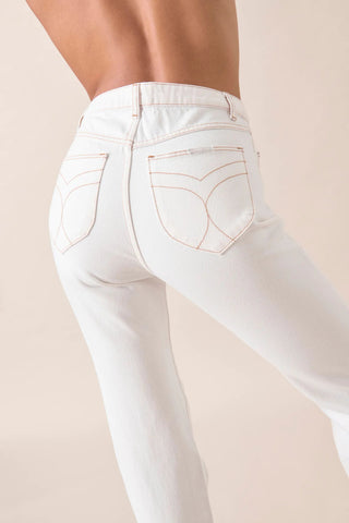 A close-up of a person wearing Rollas Classic Straight Ankle Denim in 80s White, featuring high-waisted retro style and straight legs with curved-stitched back pockets, standing against a neutral background.