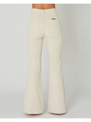 A person is seen from behind wearing Rollas East Coast Flare Corduroy jeans in light beige, featuring two back pockets and a black label on the right pocket, capturing a relaxed coastal living vibe against a plain light background.
