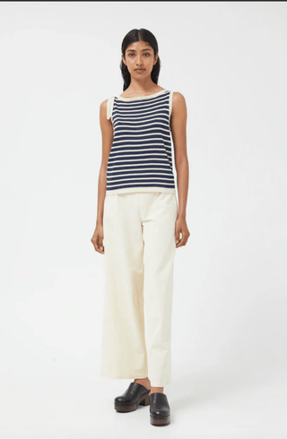 A woman faces forward, wearing the Compania Fantastica Nautical Stripe Knit Tank Top-FINAL SALE with a boat neckline, paired with wide-leg cream pants and black platform shoes against a plain white background.